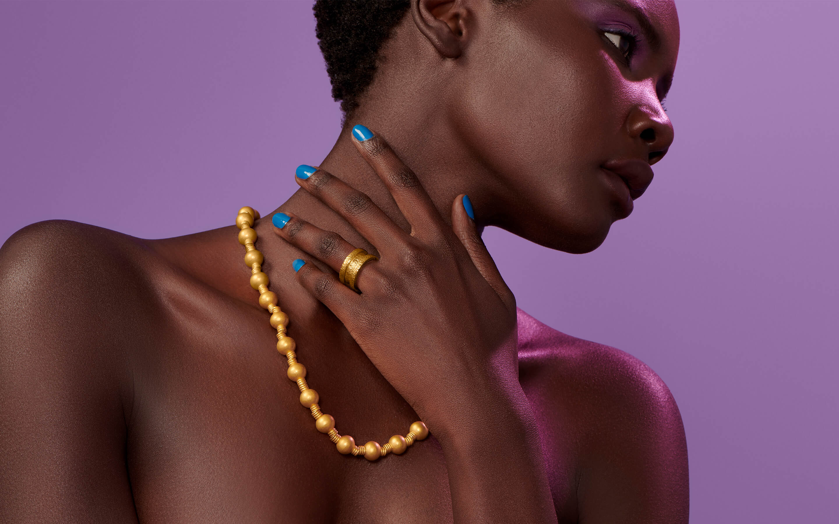 Woman model wearing Auvere 22 and 24 karat gold necklace and ring
