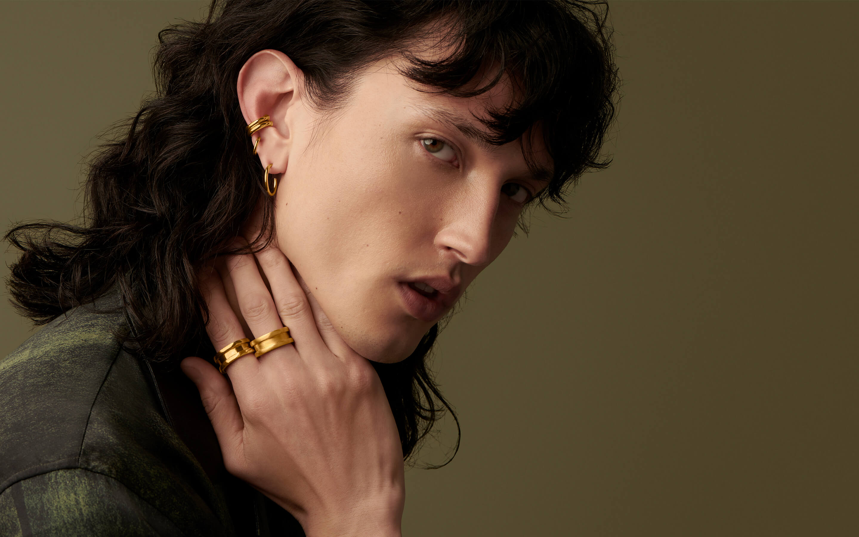 Male model wearing Auvere 22 and 24 karat gold rings and earrings