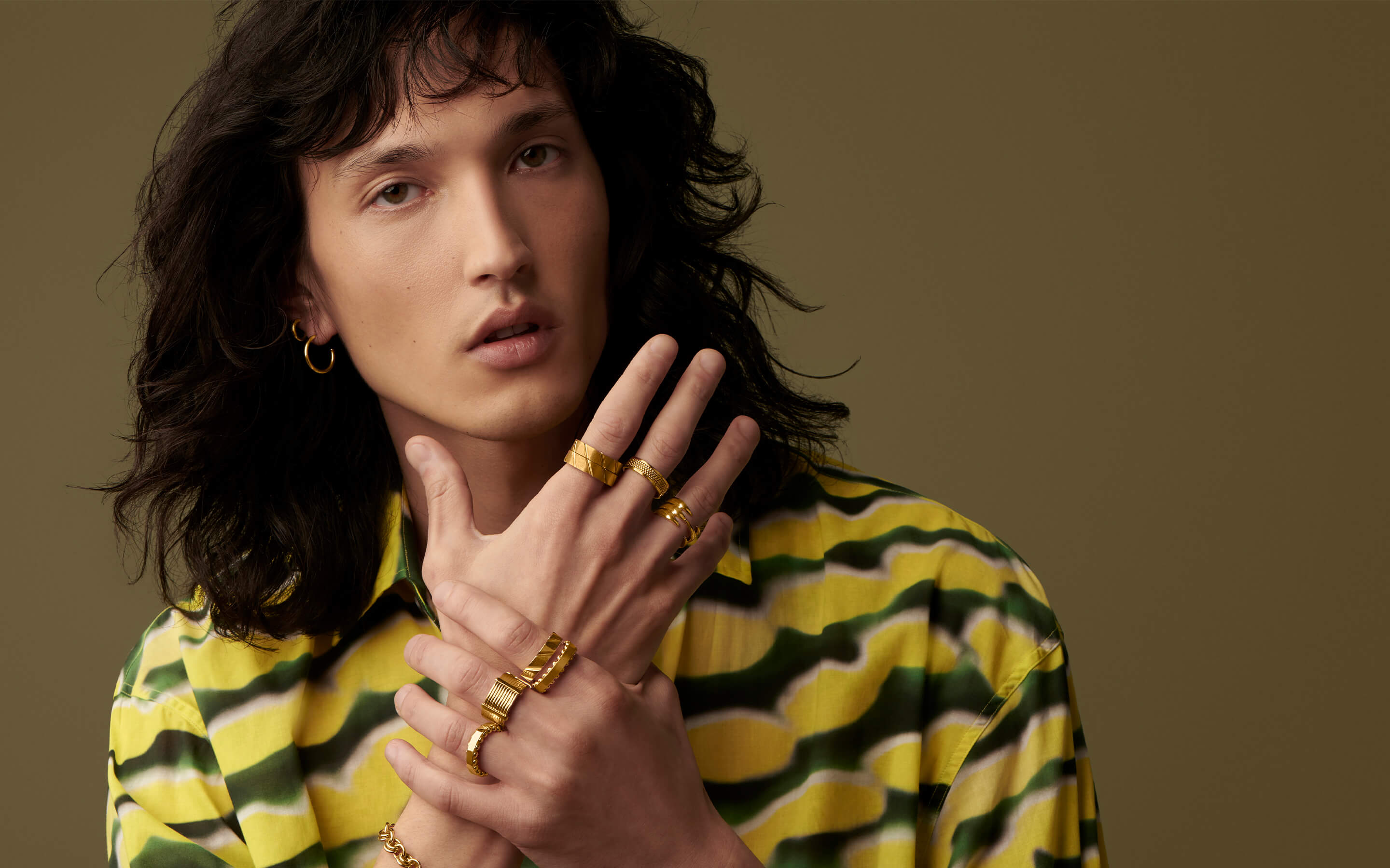 Male model wearing Auvere 22 and 24 karat gold rings, earrings and bracelets
