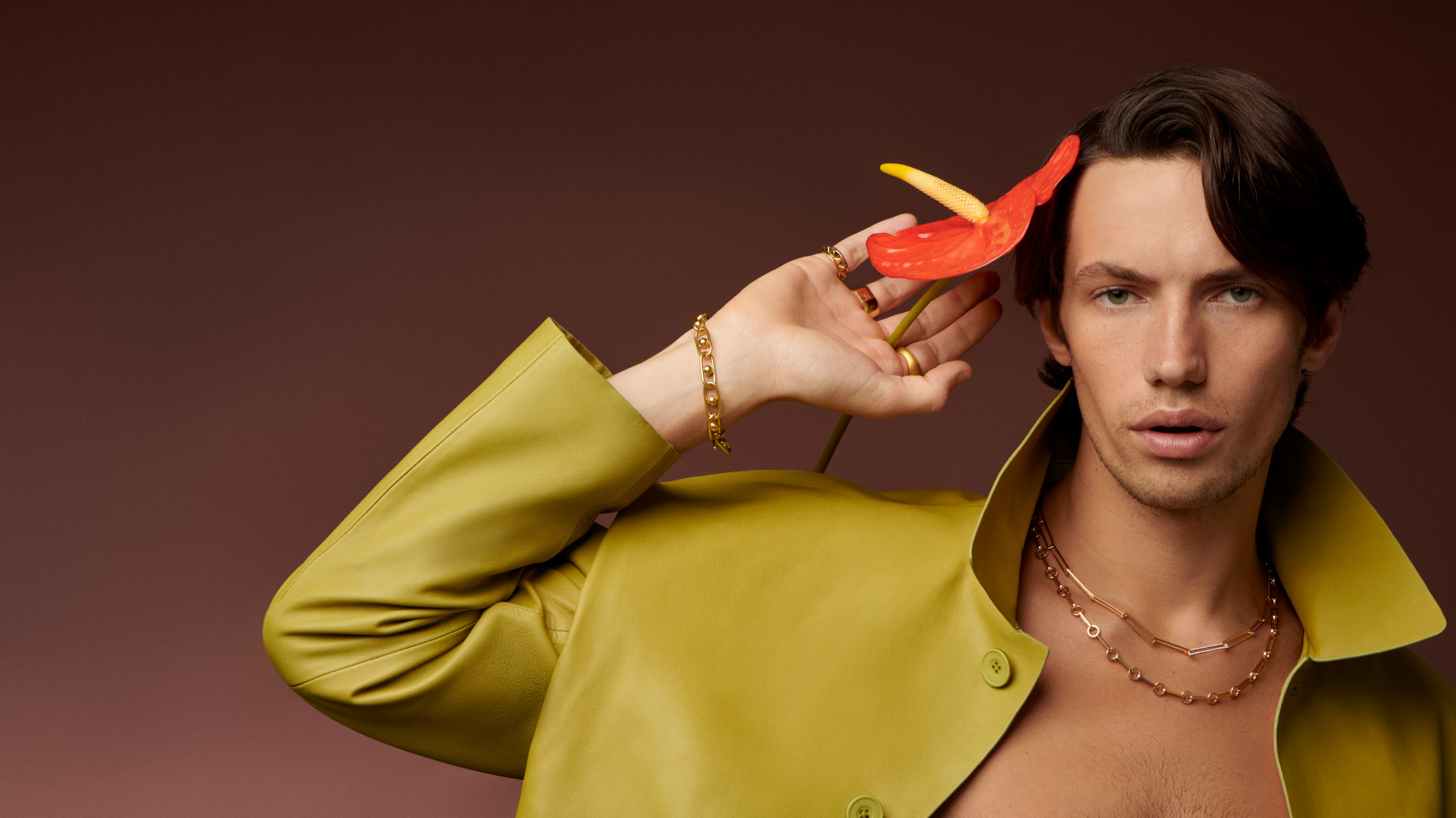 Model in profile wearing gold chain jewelry against a dark background