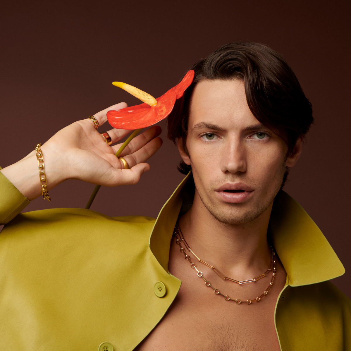 Model in profile wearing gold chain jewelry against a dark background